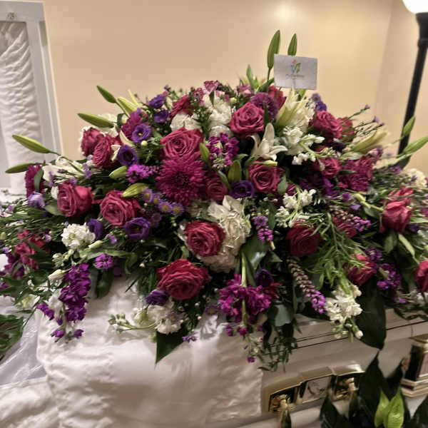 Large pink and purple floral casket spray with white accents