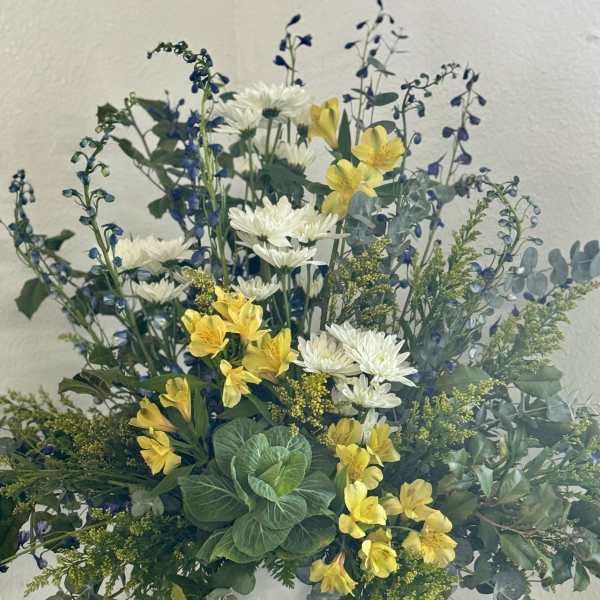 White and yellow flowers in a white pedestal vase