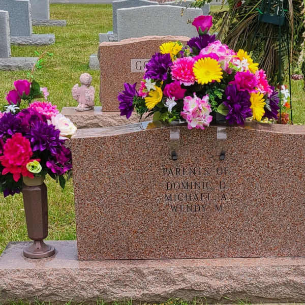 Colorful floral cemetery arrangement around a gravestone