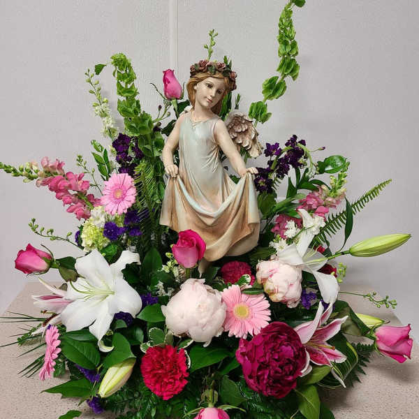 Floral arrangement with a figurine centerpiece and pink, white, and purple flowers
