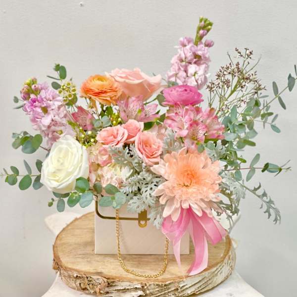 Pastel flower arrangement in a white box with a pink ribbon