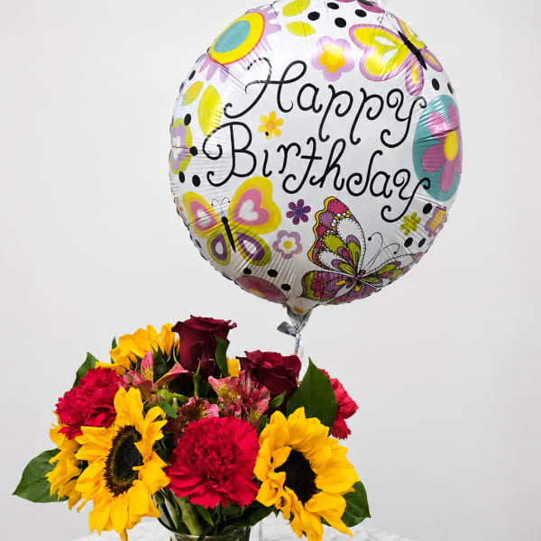 Birthday balloon above a vase of sunflowers, roses, and carnations