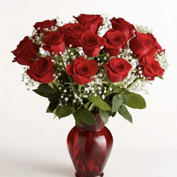 Red roses arranged in a red glass vase with baby's breath
