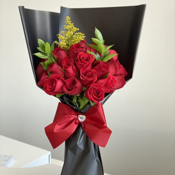Bouquet of red roses wrapped in black paper with a red ribbon