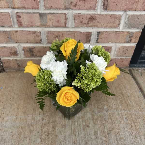 Yellow roses and white carnations in a glass vase