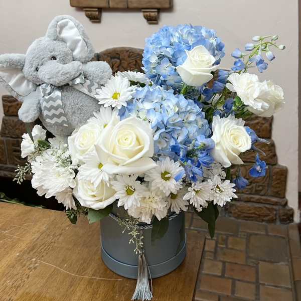 Blue and white flower arrangement with a plush elephant in a hatbox