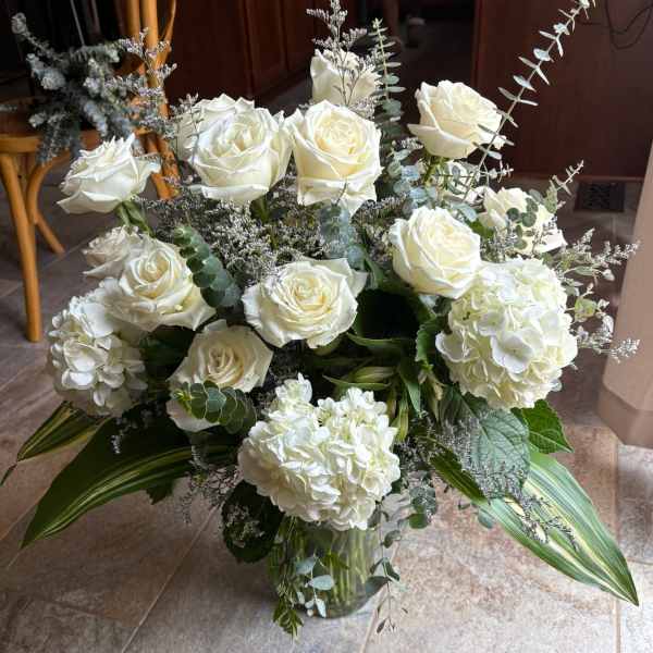 White roses and hydrangeas arranged in a glass vase