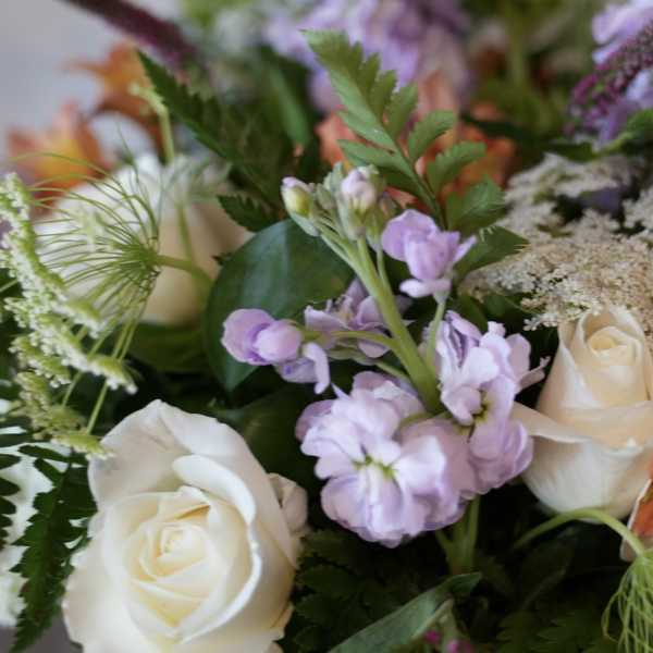Bouquet of white roses and lavender flowers with mixed greenery