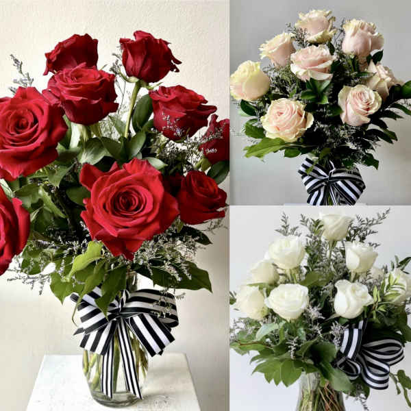Bouquets of red, blush, and white roses in glass vases with striped ribbons