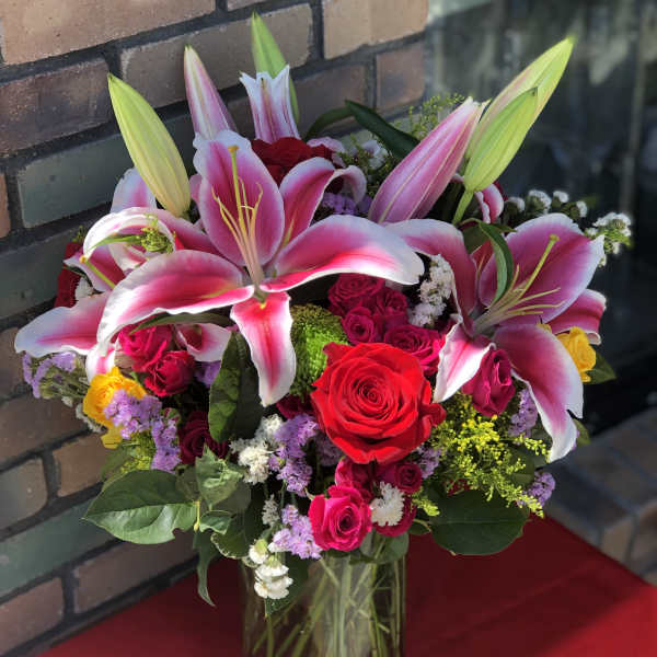 Bouquet of pink lilies and red roses in a glass vase