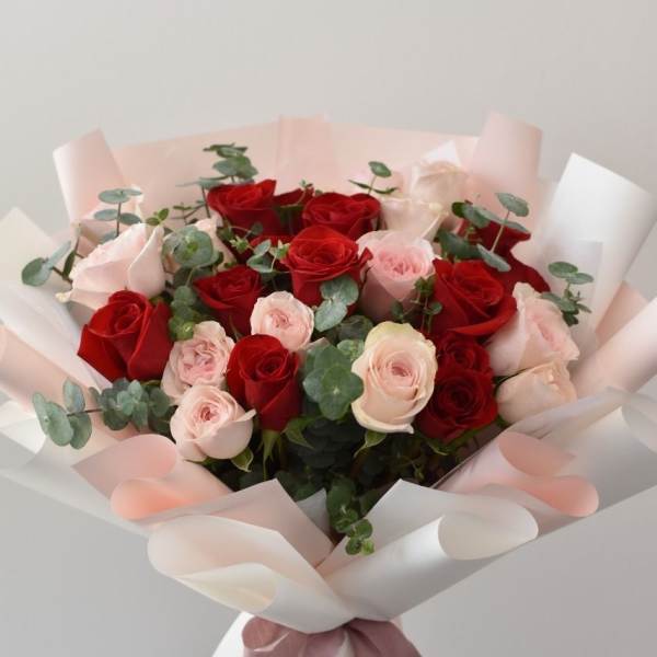 Bouquet of red and pale pink roses wrapped in white paper