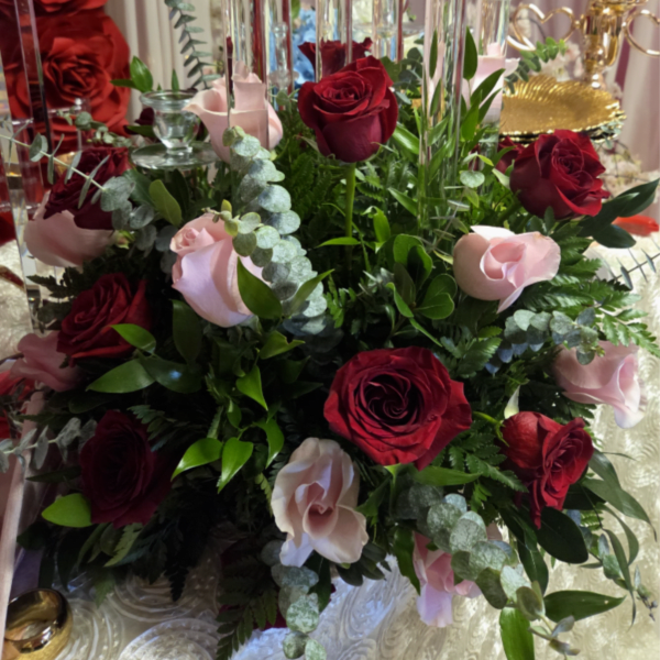 Red and pale pink roses arranged with greenery in a tall centerpiece