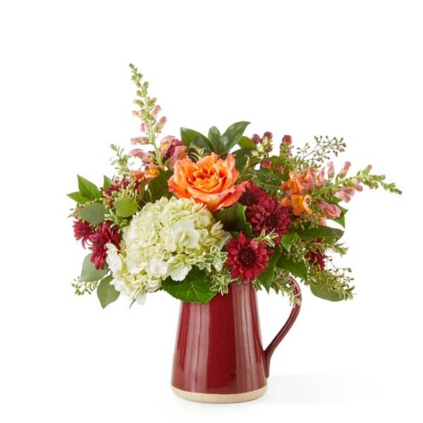 Mixed bouquet in a red ceramic pitcher vase with orange and white blooms