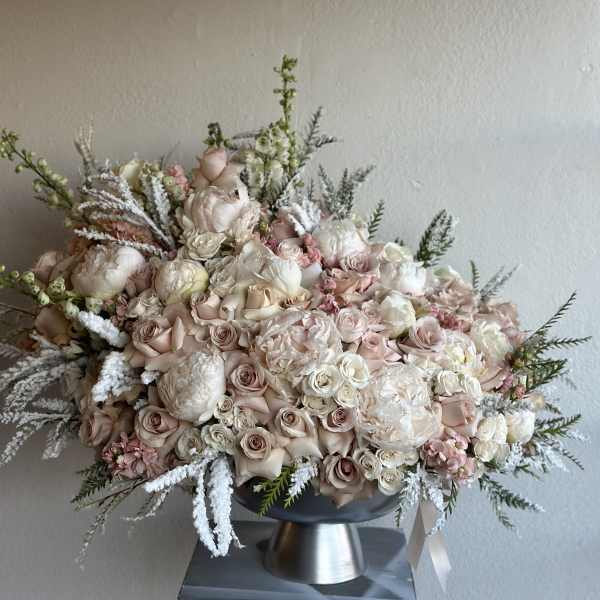 Large blush and white floral arrangement in a pedestal vase