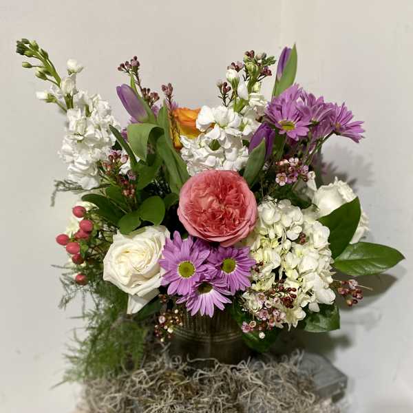 Mixed bouquet with pink, white, purple, and orange flowers in a dark vase