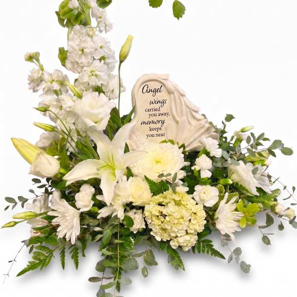 White sympathy floral arrangement with a memorial plaque and angel wings