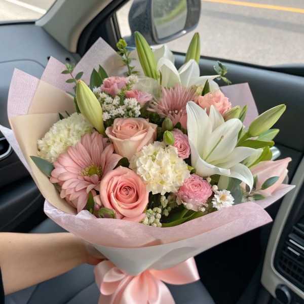 Pink and white bouquet with roses, lilies, and gerbera daisies wrapped in pastel paper