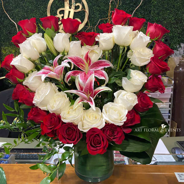 Red and white roses with pink lilies in a glass vase