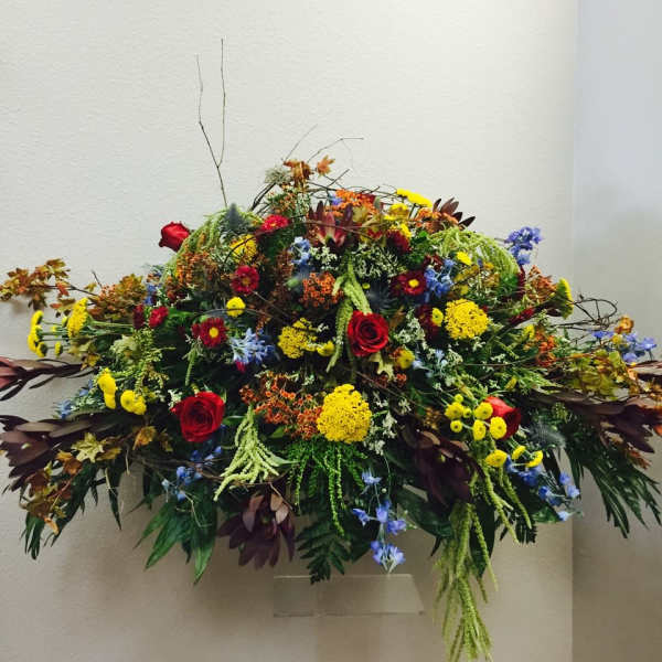 Large cascading arrangement of red, yellow, and blue flowers in an asymmetrical display.