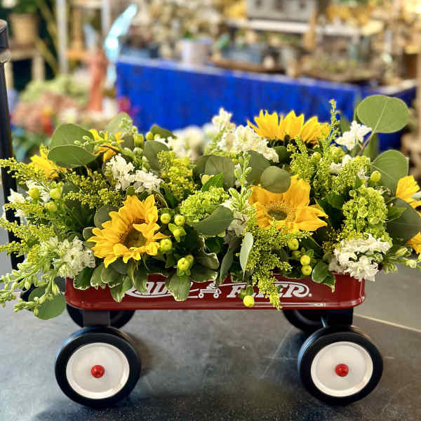 Yellow sunflower arrangement in a red wagon with white flowers