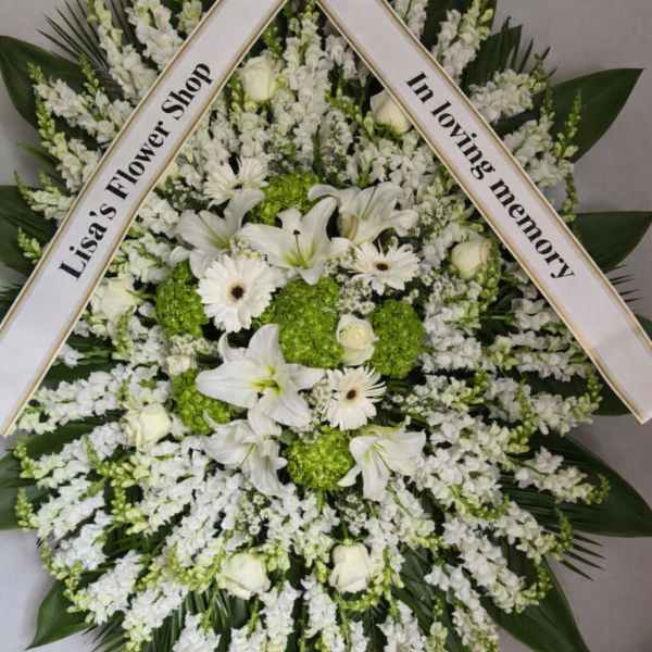 White funeral standing spray with lilies, roses, and daisies