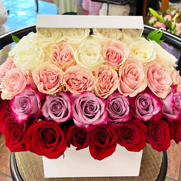 Boxed arrangement of roses in white, pink, lavender, and red