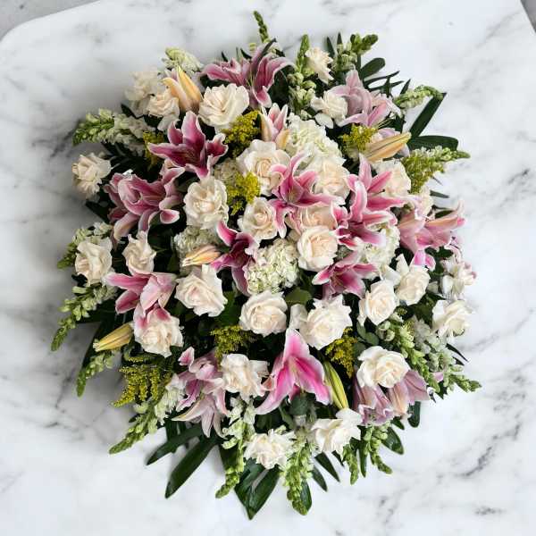 Pink lilies and white roses arranged in a round bouquet