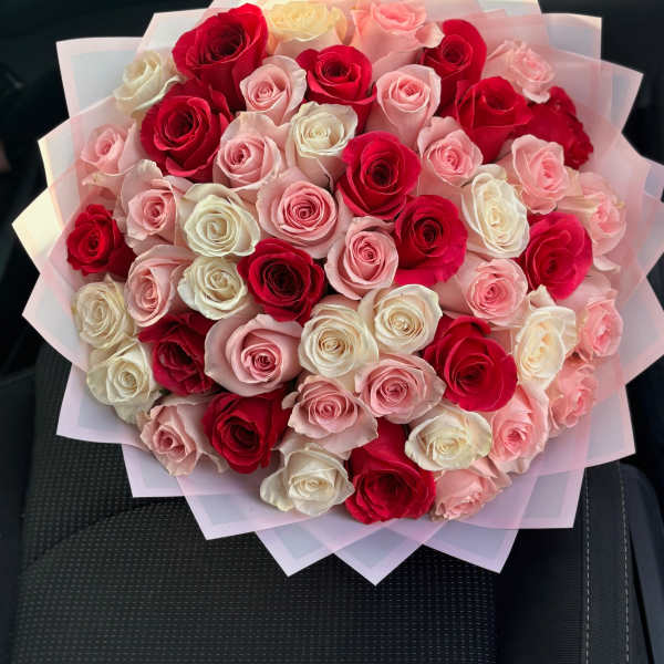 Bouquet of red, pink, and white roses wrapped in pale pink paper