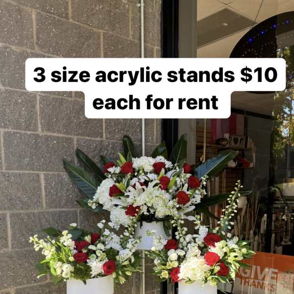 Three floral arrangements on clear acrylic stands with red and white flowers