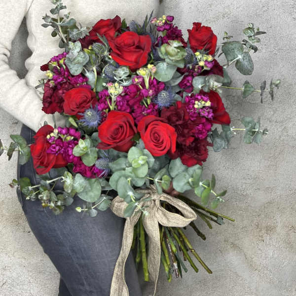 Hand-tied bouquet of red roses and magenta flowers with eucalyptus