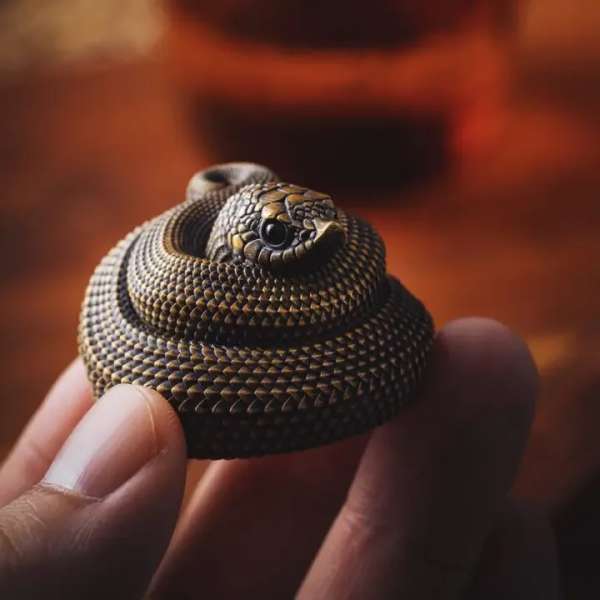 A small coiled snake figurine held between fingers