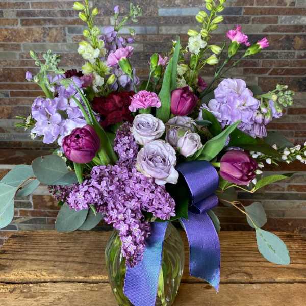 Purple and lavender bouquet in a glass vase with a ribbon