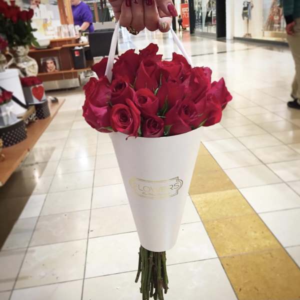Handheld bouquet of red roses wrapped in a white cone