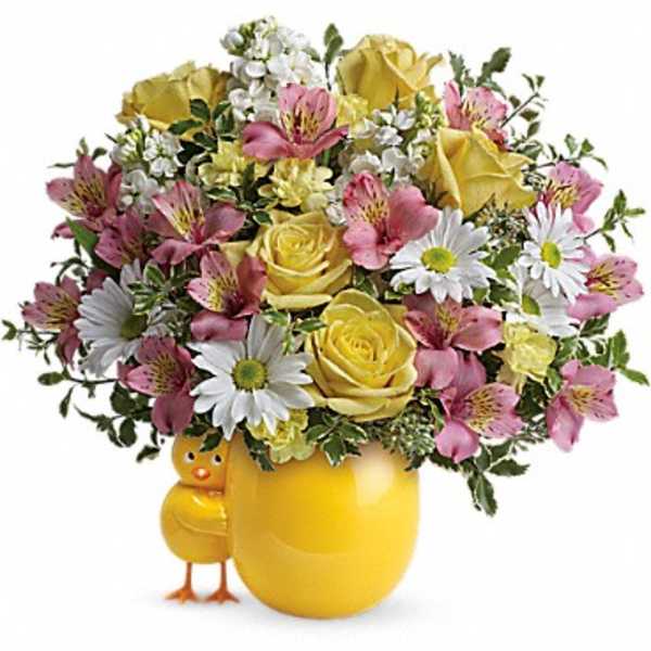 Yellow roses and pink flowers arranged in a yellow vase with a small chick figurine