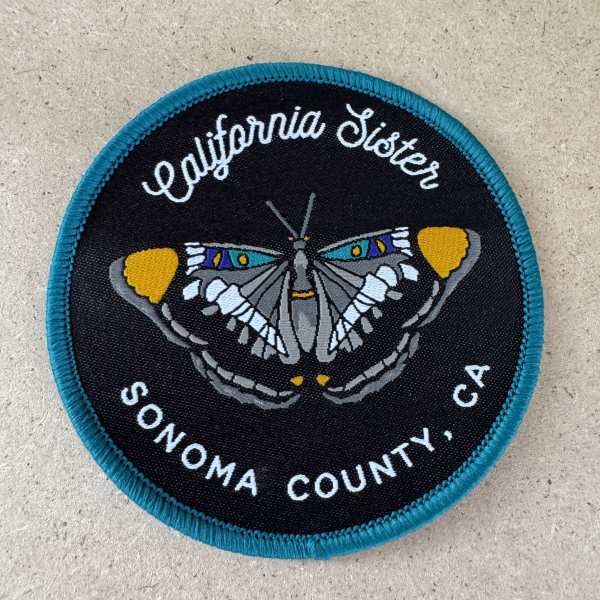 Round California Sister patch with a butterfly design and text
