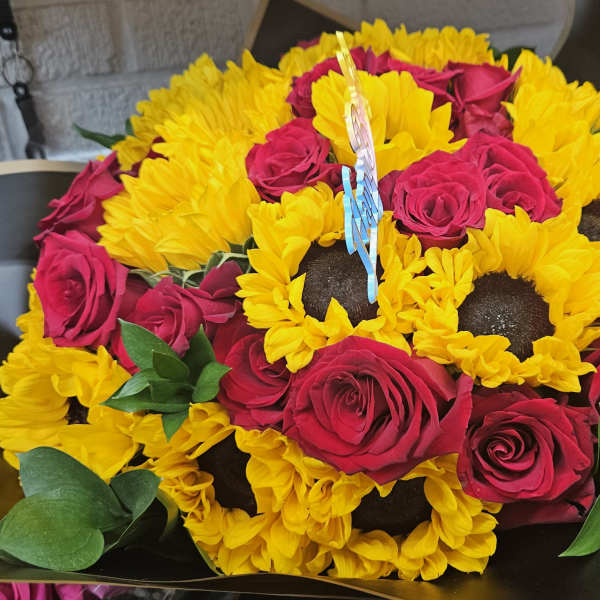 Bouquet of yellow sunflowers and hot pink roses in dark wrapping
