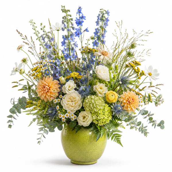 Mixed bouquet in a green vase with blue, white, yellow, and peach flowers
