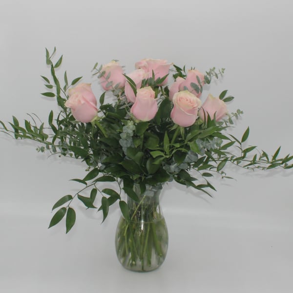 Pink roses in a clear glass vase with airy greenery