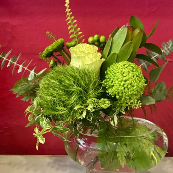 Green floral arrangement in a clear glass bowl vase