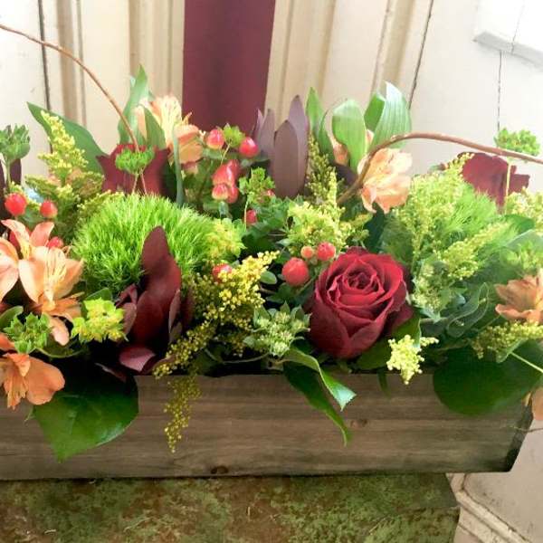 Rectangular floral arrangement with red roses and peach flowers in a wooden box