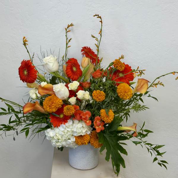 Bright mixed bouquet with gerbera daisies, roses, calla lilies, and hydrangea in a white vase