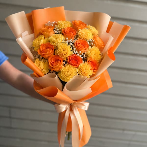 Bouquet of orange roses and yellow carnations wrapped in orange paper