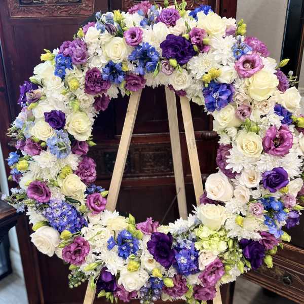 Large floral wreath with white, purple, pink, and blue blooms on an easel
