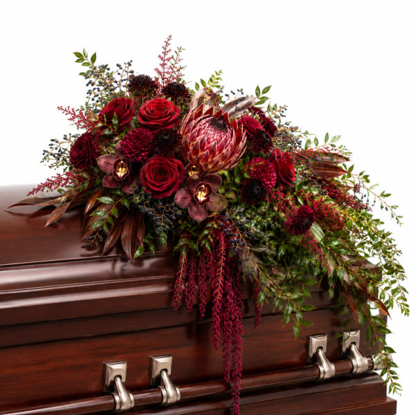 Deep red floral spray on a polished wooden casket