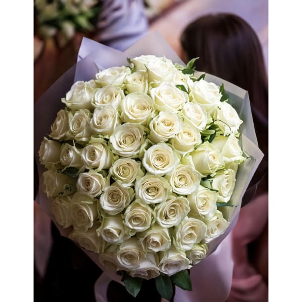 Bouquet of white roses wrapped in pale paper