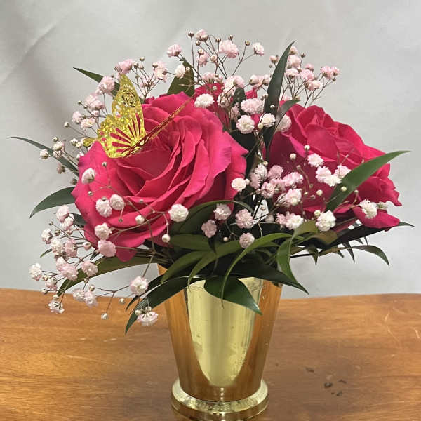 Pink roses in a gold vase with baby's breath and a butterfly pick