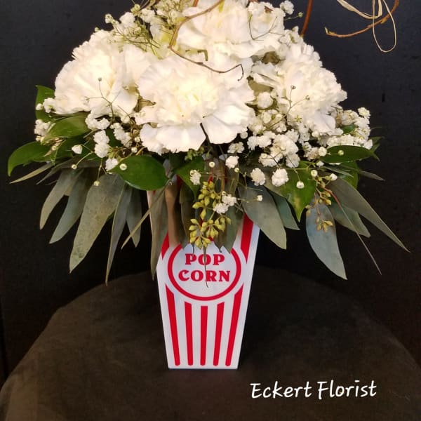 White floral arrangement in a popcorn box-shaped container