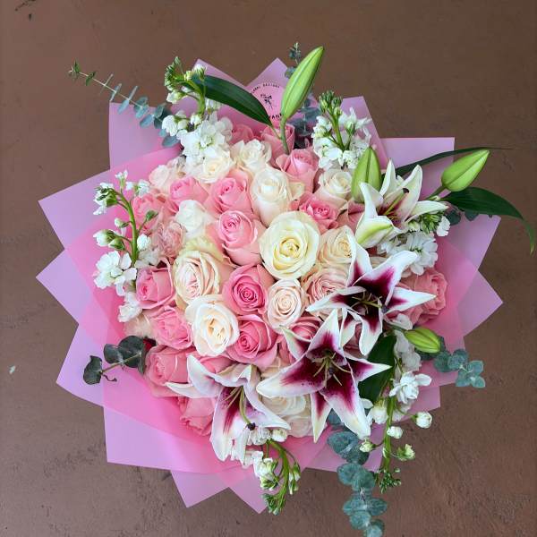 Pink and white rose bouquet with lilies wrapped in pink paper