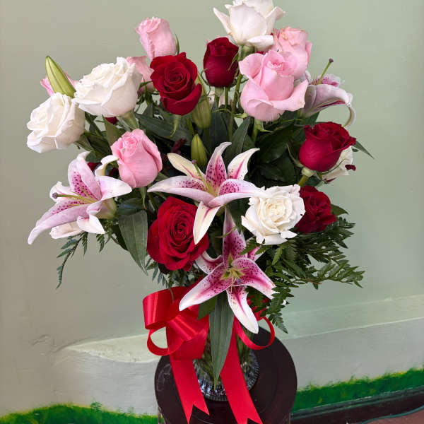 Bouquet of red, pink, and white roses with pink lilies and a red ribbon