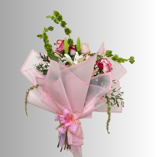 Pink-wrapped bouquet with roses, lilies, and trailing greenery
